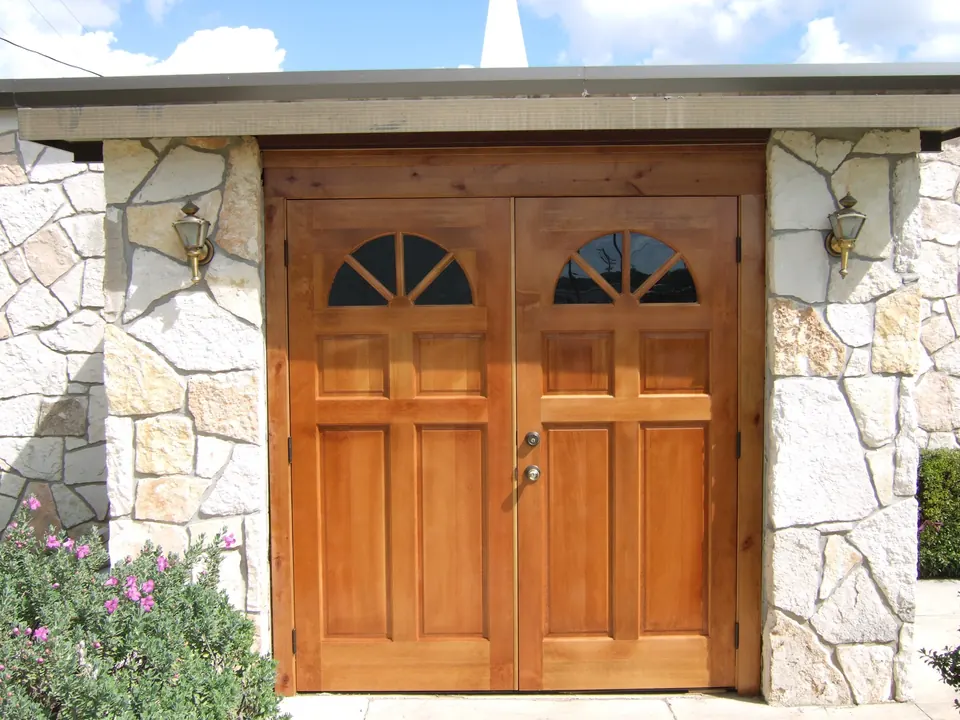 Double wood doors with arched lights, framed in native stone