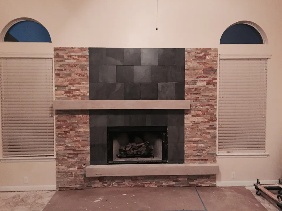 Fireplace surround with stacked stone, tile and a wood mantel