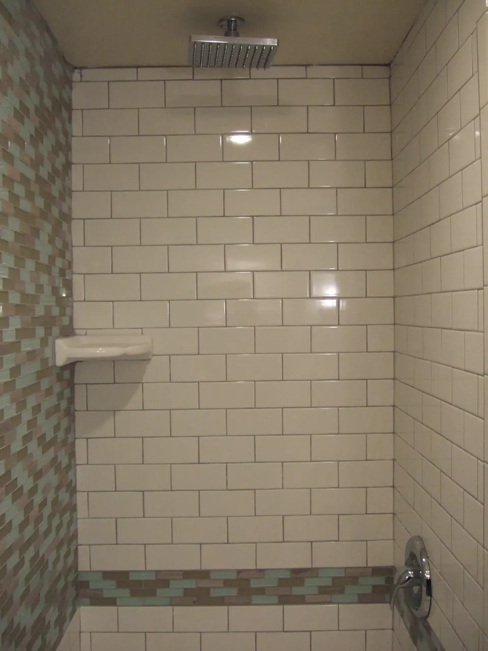 Floor-to-ceiling subway-tile shower with a mosaic accent band