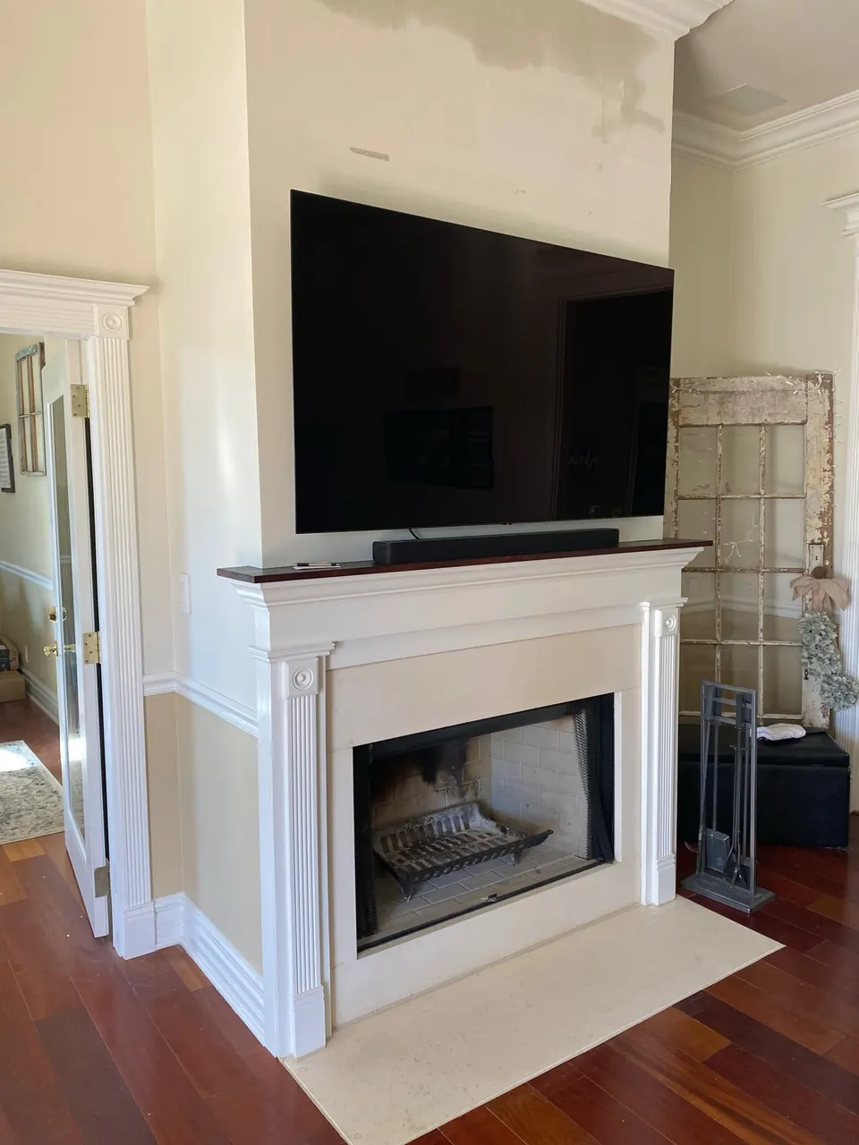 White fireplace mantel with fluted pilasters, a wood shelf and a stone hearth